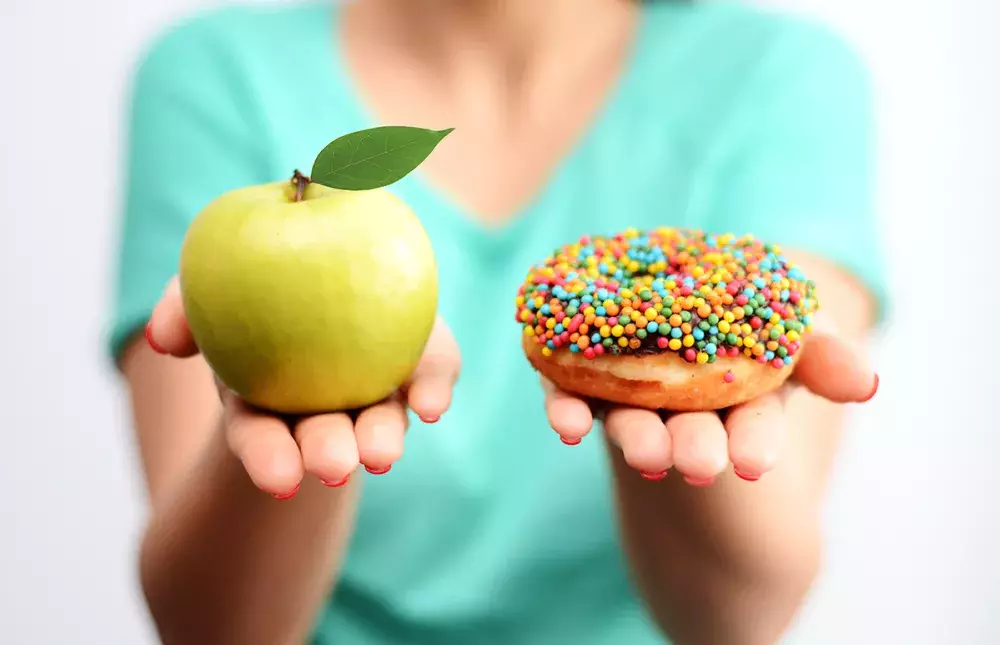 Person holding an apple and donut